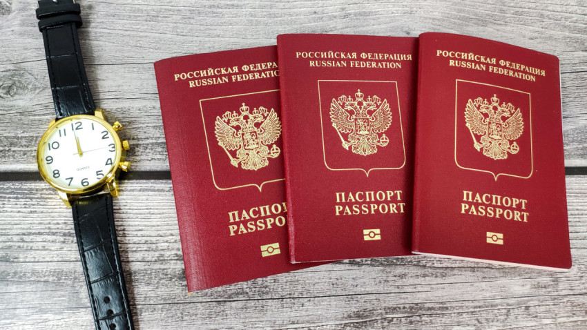 Три загранпаспорта РФ и наручные часы на деревянном фоне