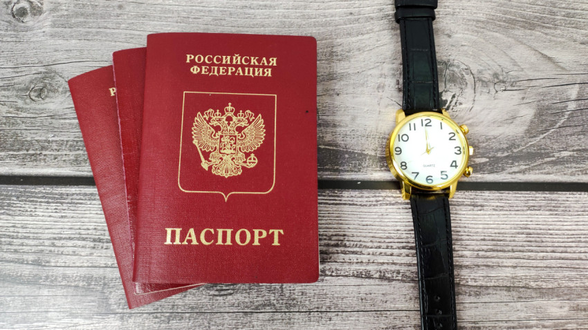 Загранпаспорта РФ и наручные часы на деревянном фоне