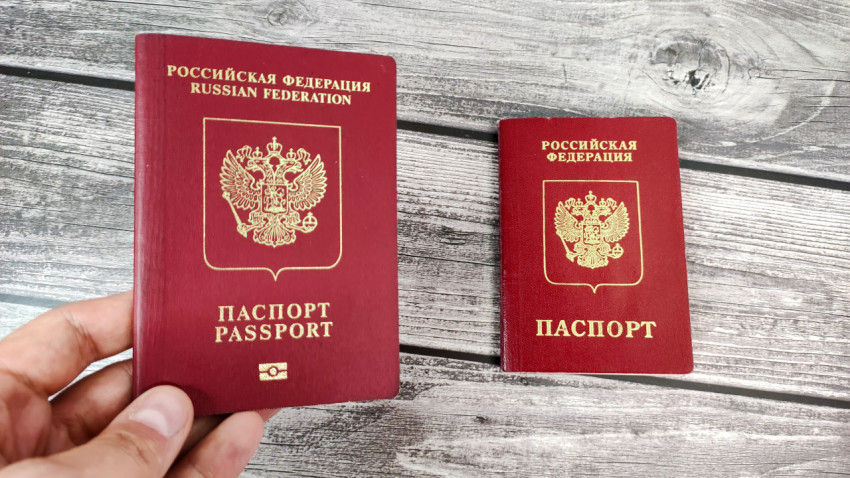 Биометрический загранпаспорт в руке на фоне загранпаспорта старого образца