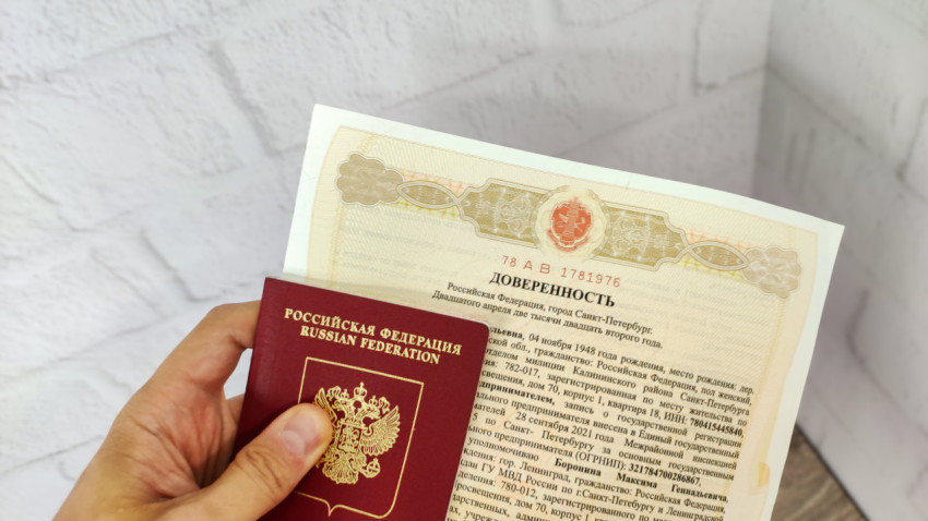 Загранпаспорт РФ и доверенность в руке на фоне стены
