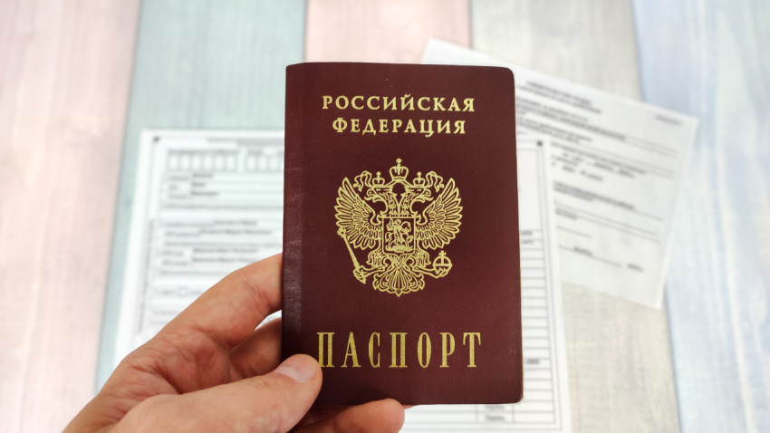 Паспорт РФ в руке на фоне анкеты и документов