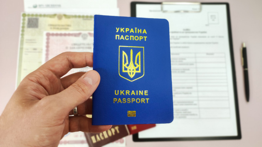 Паспорт Украины в руке на фоне документов