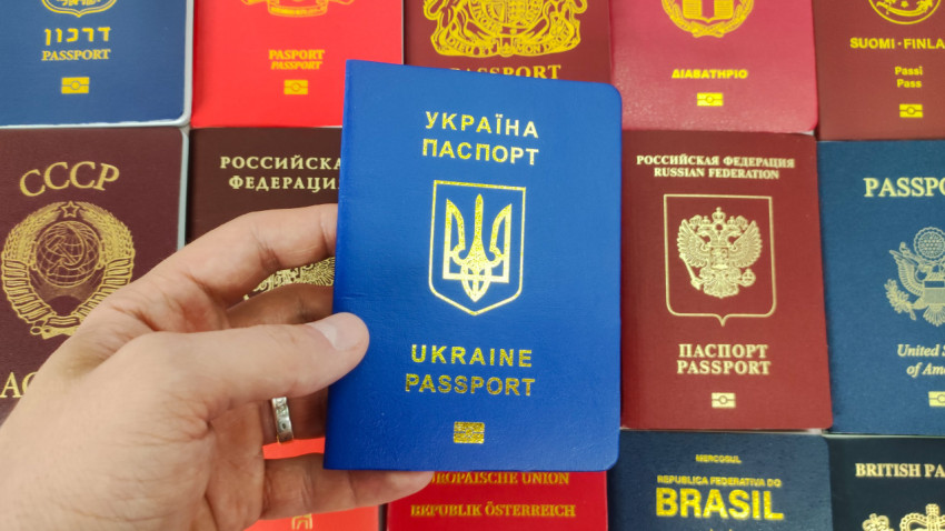 Украинский паспорт в руке на фоне паспортов разных стран
