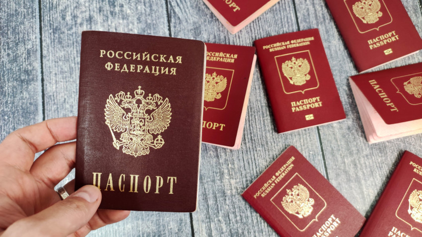 Внутренний паспорт Российской Федерации в руке на фоне загранпаспортов