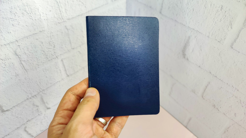 Синий паспорт в руке на фоне светлой стены