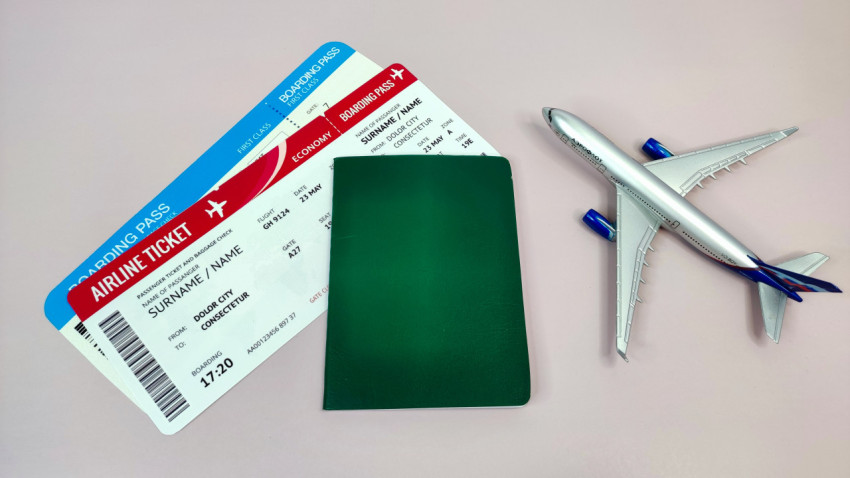 Зеленый паспорт и авиабилеты рядом с моделью самолета
