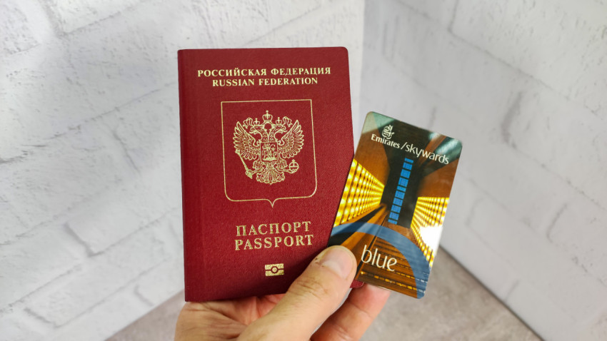 Российский загранпаспорт и карта Emirates Skywards Blue на фоне стены