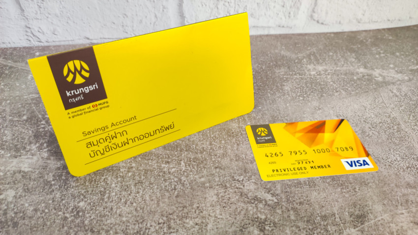 Сберегательная книжка и карта Krungsri Bank на сером фоне