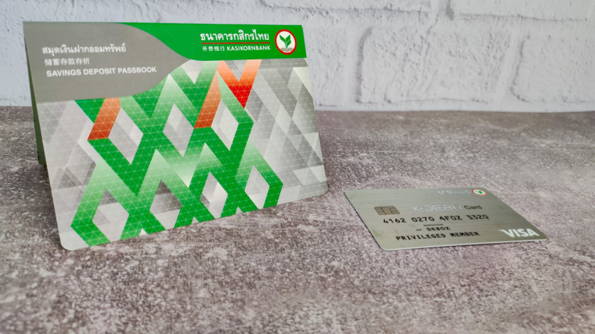 Сберегательная книжка Kasikornbank и карта Visa на серой поверхности