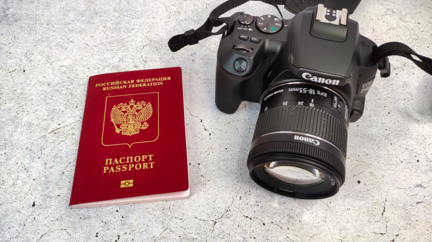 Загранпаспорт России и фотоаппарат Canon на столе