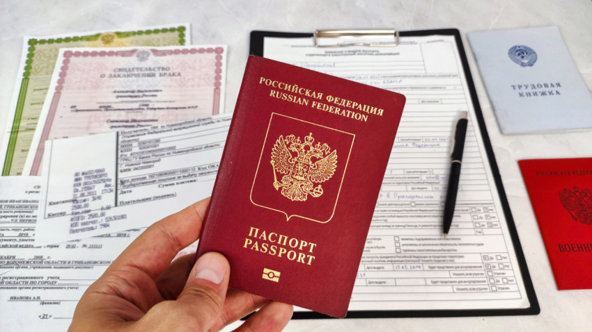 Загранпаспорт РФ в руке на фоне документов и свидетельств