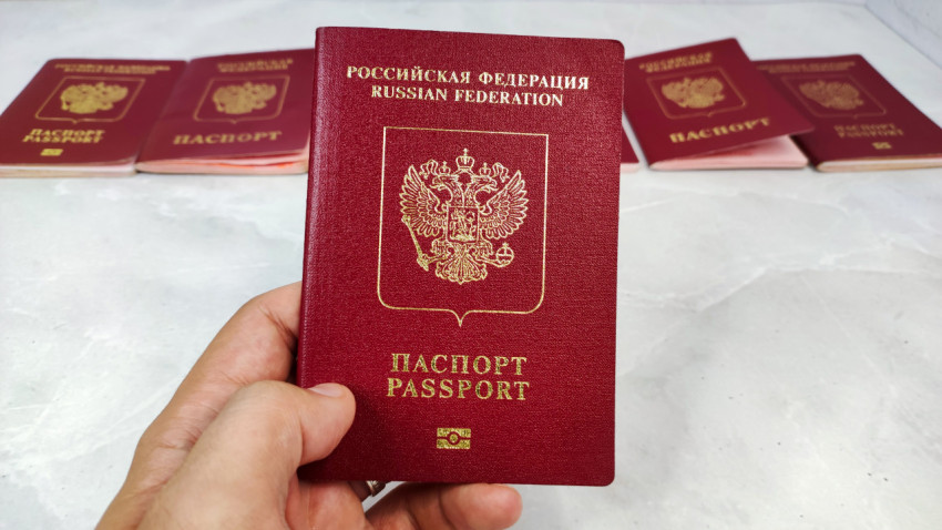 Загранпаспорт РФ в руке на фоне других паспортов