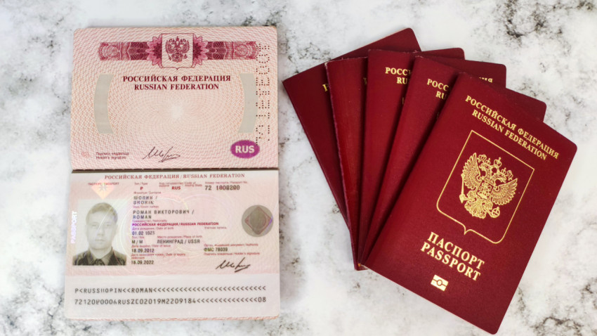 Разворот загранпаспорта РФ и стопка паспортов рядом