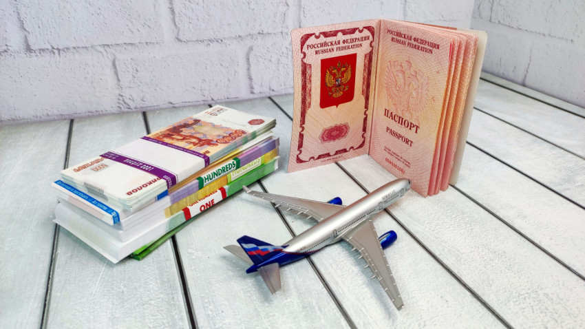 Загранпаспорт РФ и пачки банкнот рядом с моделью самолета