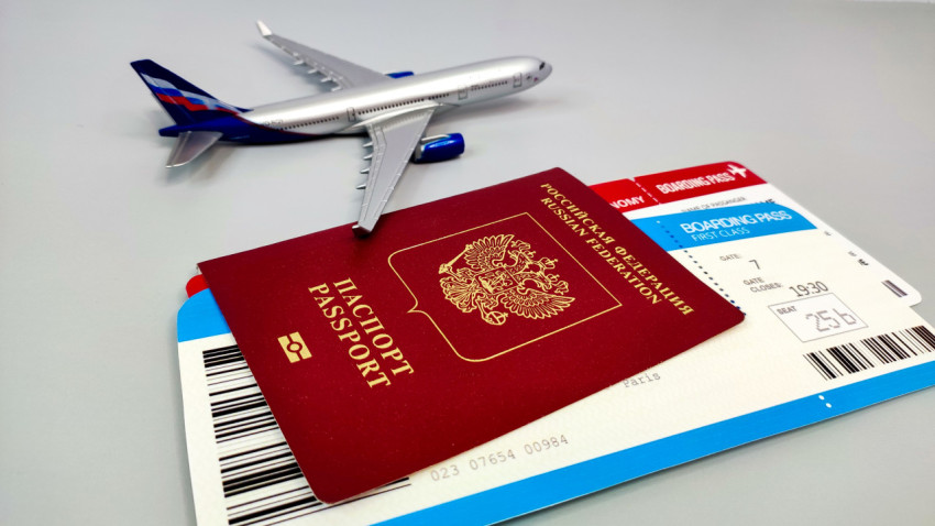 Заграничный паспорт РФ и авиабилет рядом с моделью самолета