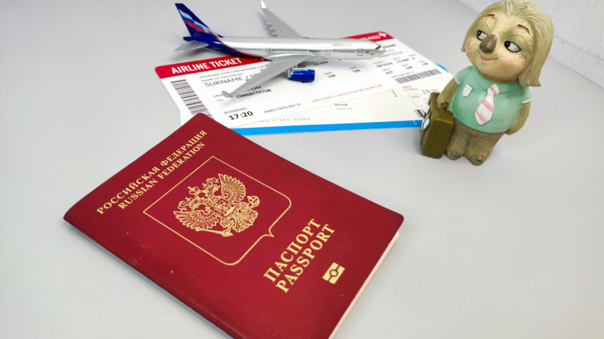 Заграничный паспорт РФ, авиабилет и фигурка путешественника