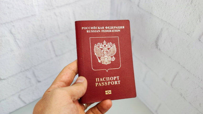 Заграничный паспорт РФ в руке на фоне белой стены