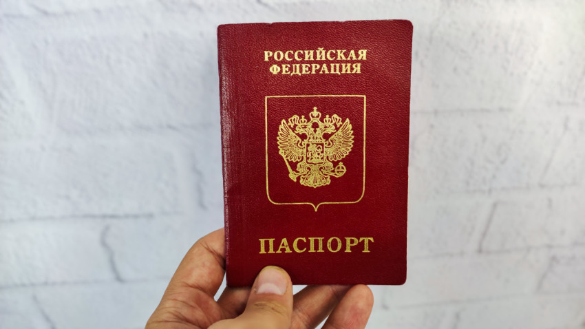 Загранпаспорт РФ в руке на фоне светлой стены