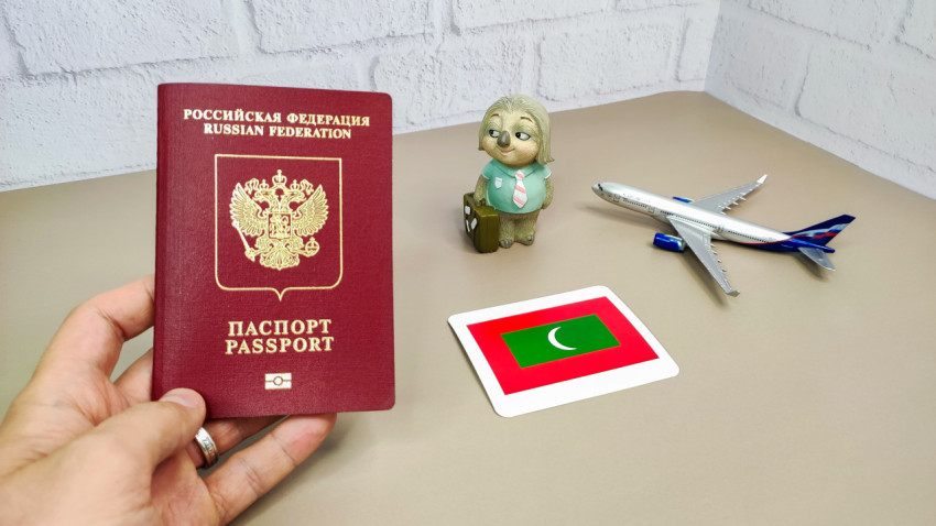 Загранпаспорт РФ в руке и флаг Мальдив