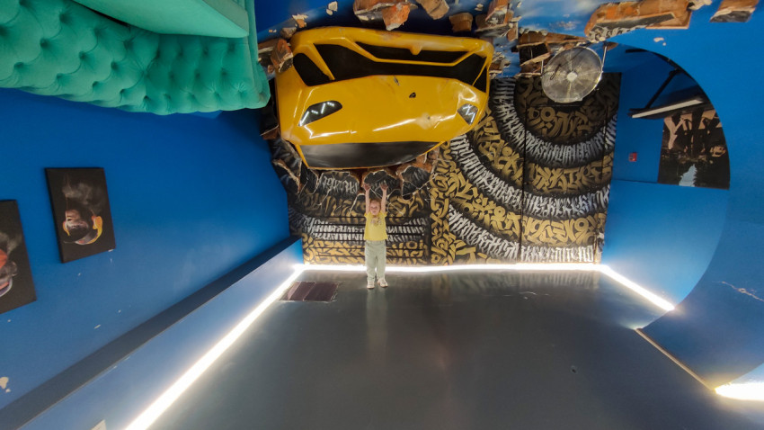 Девочка в комнате с перевёрнутым интерьером и жёлтой машиной на потолке