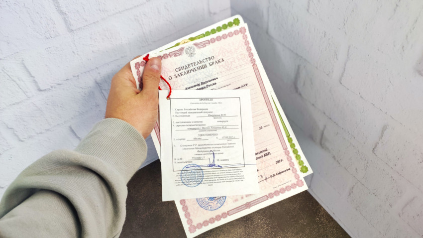Апостиль и свидетельство о браке в руке человека