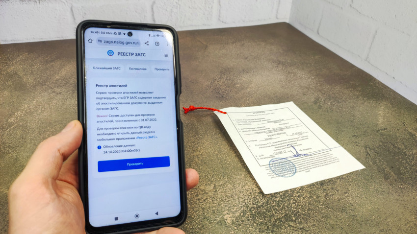 Смартфон с сайтом Реестр ЗАГС и документом с апостилем