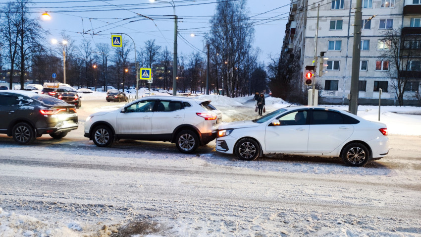 Автомобили на зимней дороге перед жилой застройкой