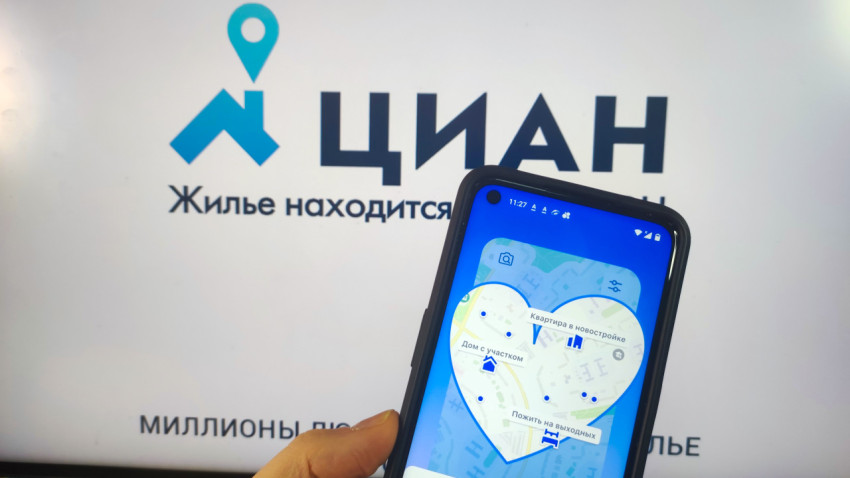 Экран смартфона с картой сервиса ЦИАН на фоне логотипа