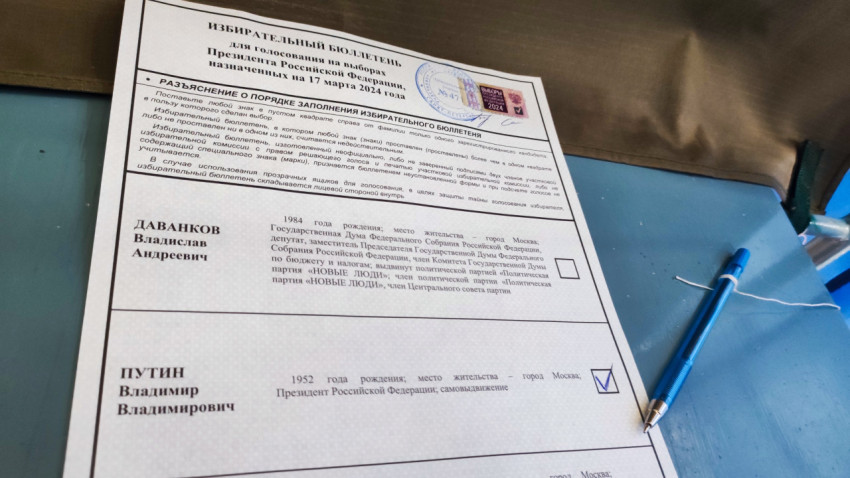 Избирательный бюллетень с отметкой и ручкой на синем столе