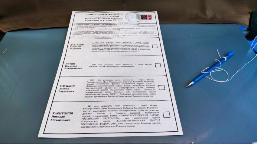 Избирательный бюллетень на синем столе в помещении участка