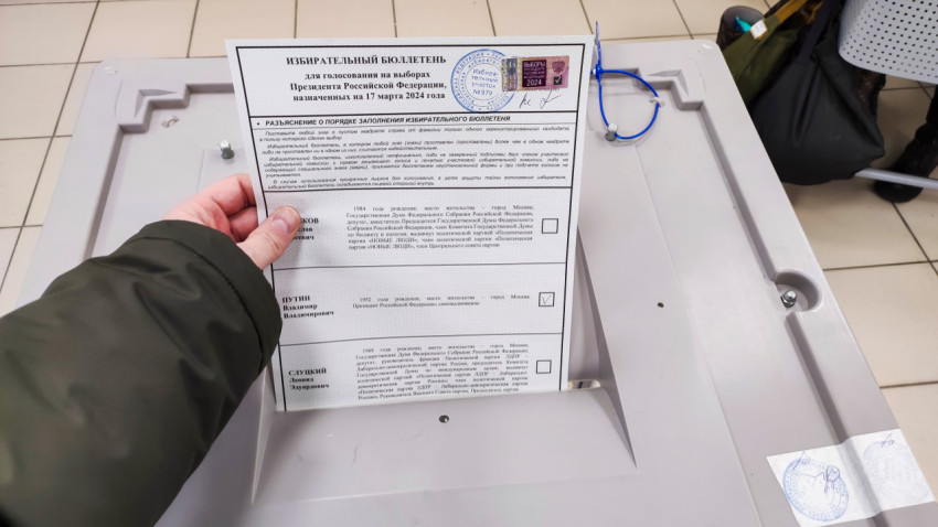 Избиратель опускает заполненный бюллетень в урну на выборах президента России 2024