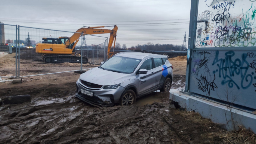 Каршеринговая машина в грязи возле экскаватора на стройке