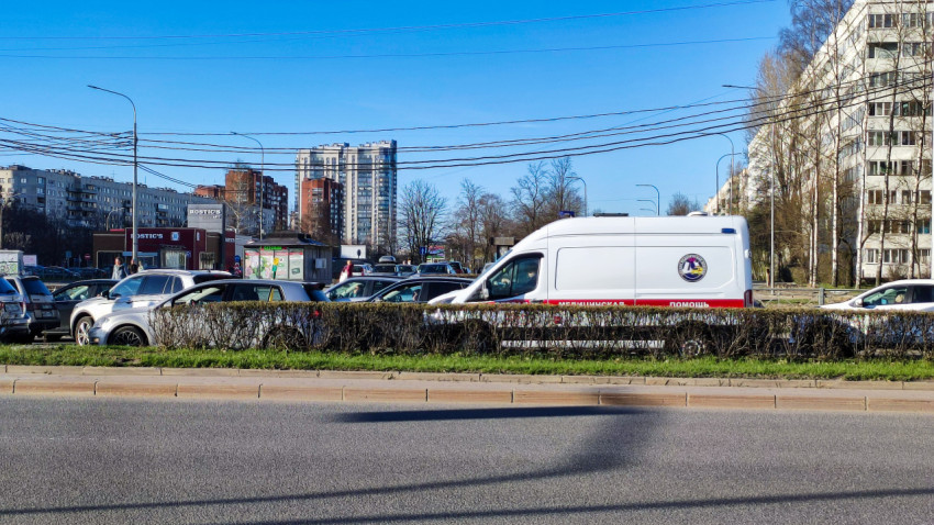 Скорая помощь в потоке автомобилей на фоне жилых домов