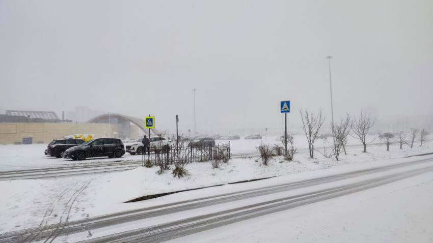 Парковка и дорожные знаки на территории торгового района в снегопад