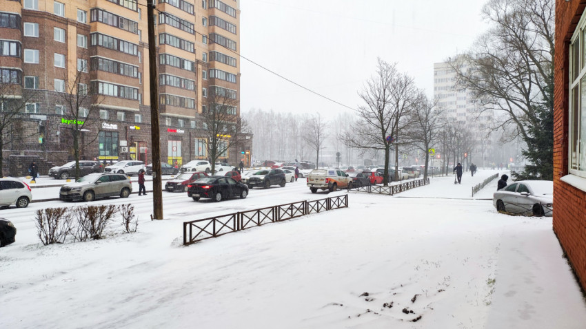 Заснеженная городская улица с автомобилями и жилыми домами