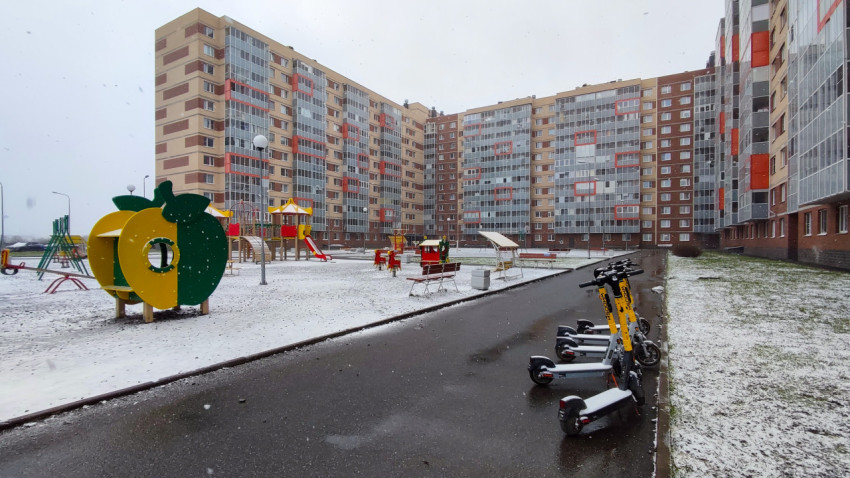Детская площадка и электросамокаты на фоне жилых домов зимой