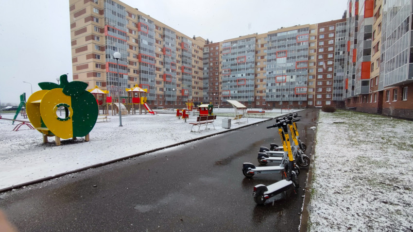 Двор с детской площадкой и электросамокатами в новостройке зимой