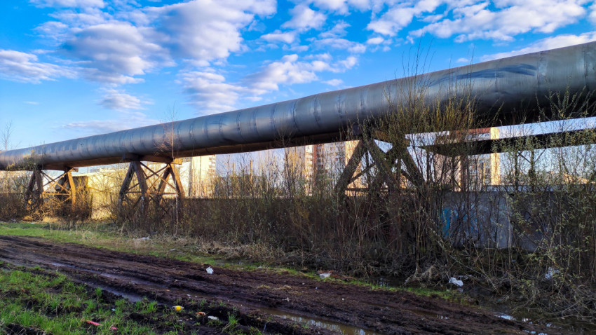 Воздушный трубопровод над землёй на фоне городской застройки