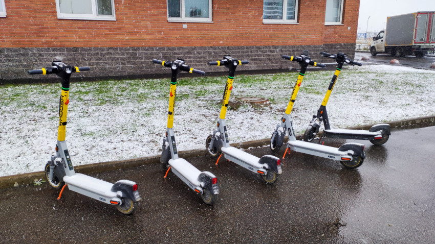 Ряд электросамокатов Whoosh на фоне кирпичного жилого здания