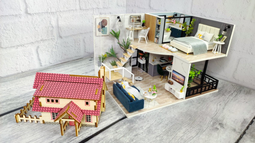 Макет интерьера квартиры и модель коттеджа на деревянной поверхности