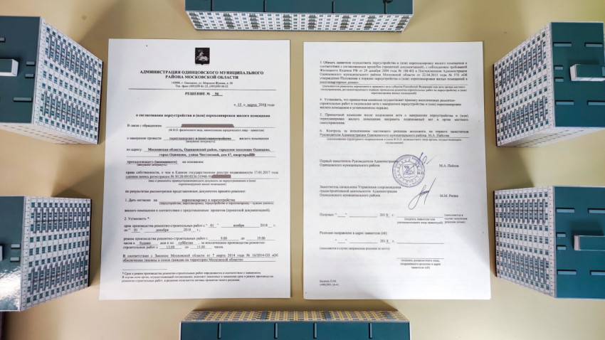 Документы о согласовании перепланировки, окруженные бумажными макетами домов