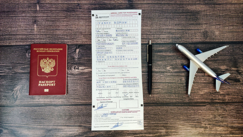 Миграционная карта, паспорт и модель самолёта на деревянной поверхности