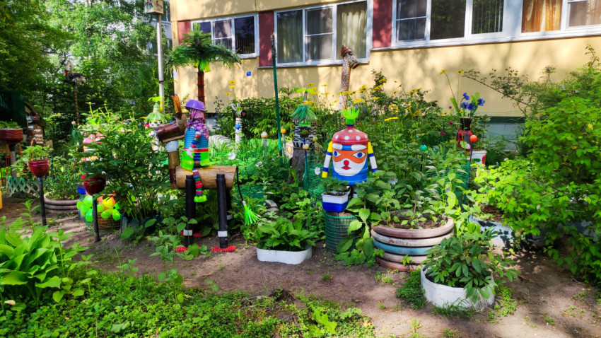 Двор с декоративными фигурами и растениями возле жилого дома