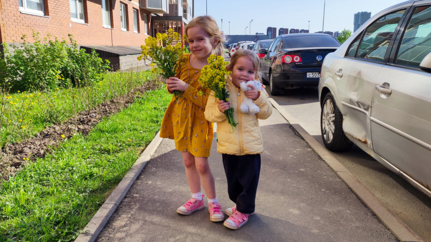 Две девочки с букетами цветов в жилом районе