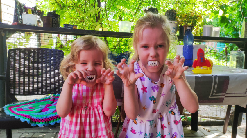 Две девочки с игрушечными клыками на веранде