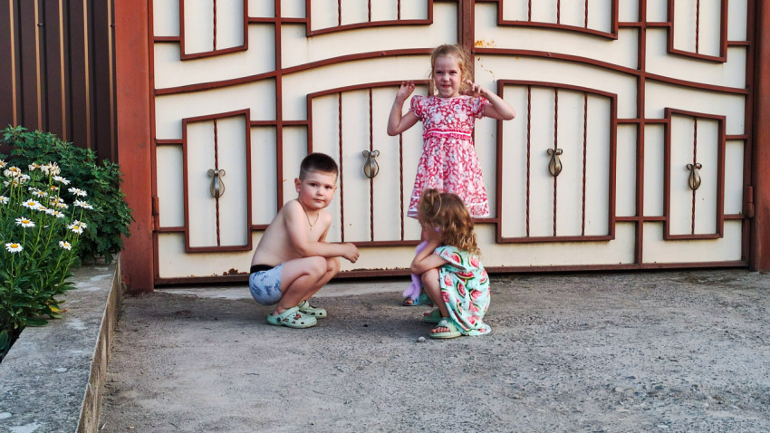 Трое детей стоят и сидят у ворот