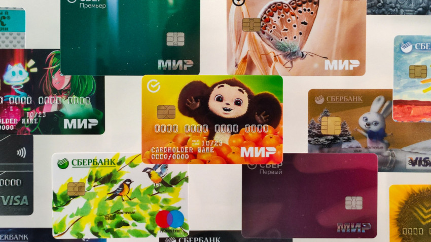Фрагмент стенда с банковскими картами Сбера, включая карту «Мир» с Чебурашкой