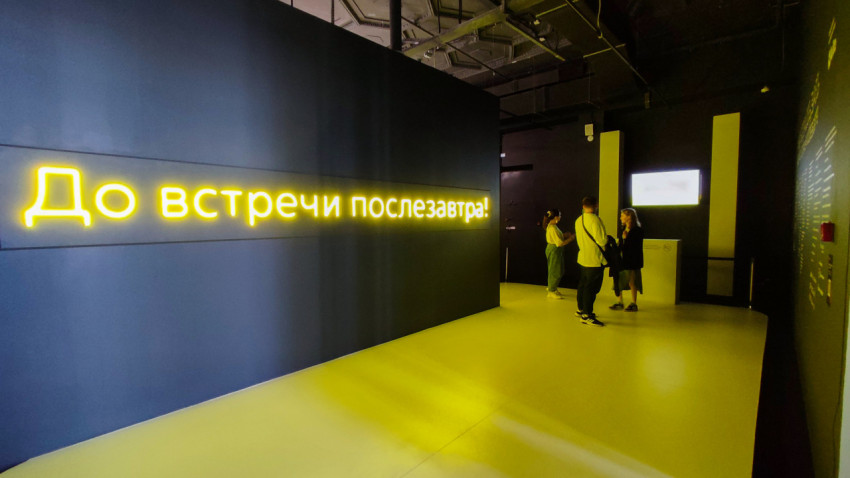 Финальная зона выставки с неоновой надписью и посетителями