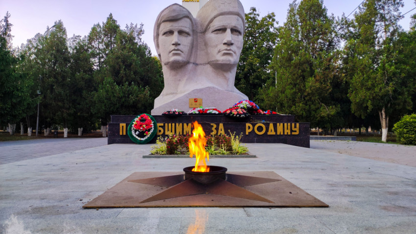 Вечный огонь на фоне скульптуры воинов у мемориала в парке Прохладного