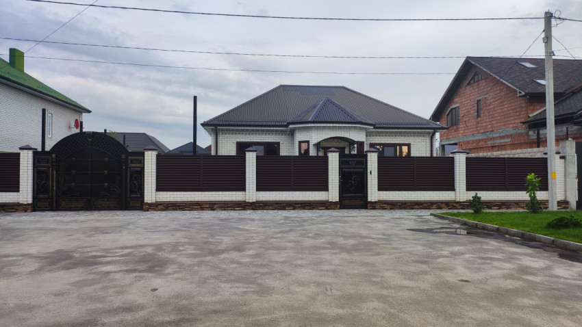 Высокий забор с коваными воротами перед жилым домом